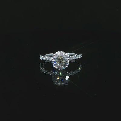 Modern round solitaire-style engagement ring with a hidden halo and diamond-accented white gold band.