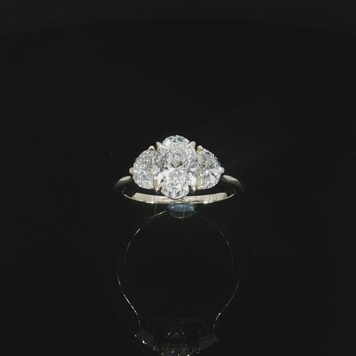 Classic three-stone engagement ring with an oval center diamond and complementary half-moon side diamonds.