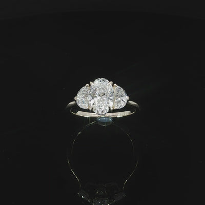 Classic three-stone engagement ring with an oval center diamond and complementary half-moon side diamonds.
