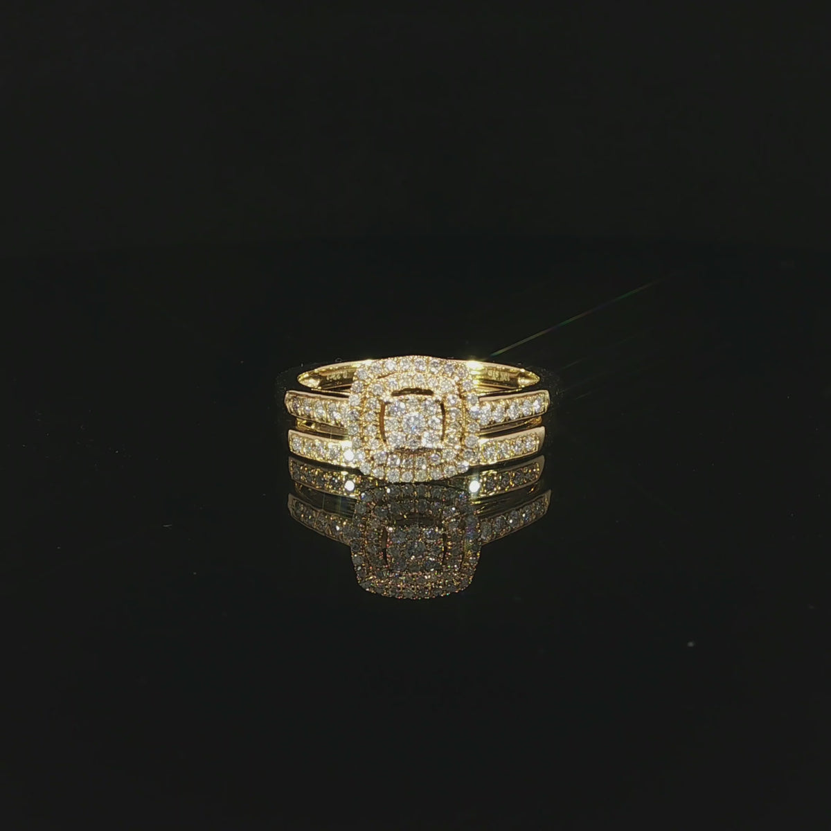 Video of a 10K yellow gold double-halo bridal set resting on a glossy black surface, with both diamond bands reflected below.