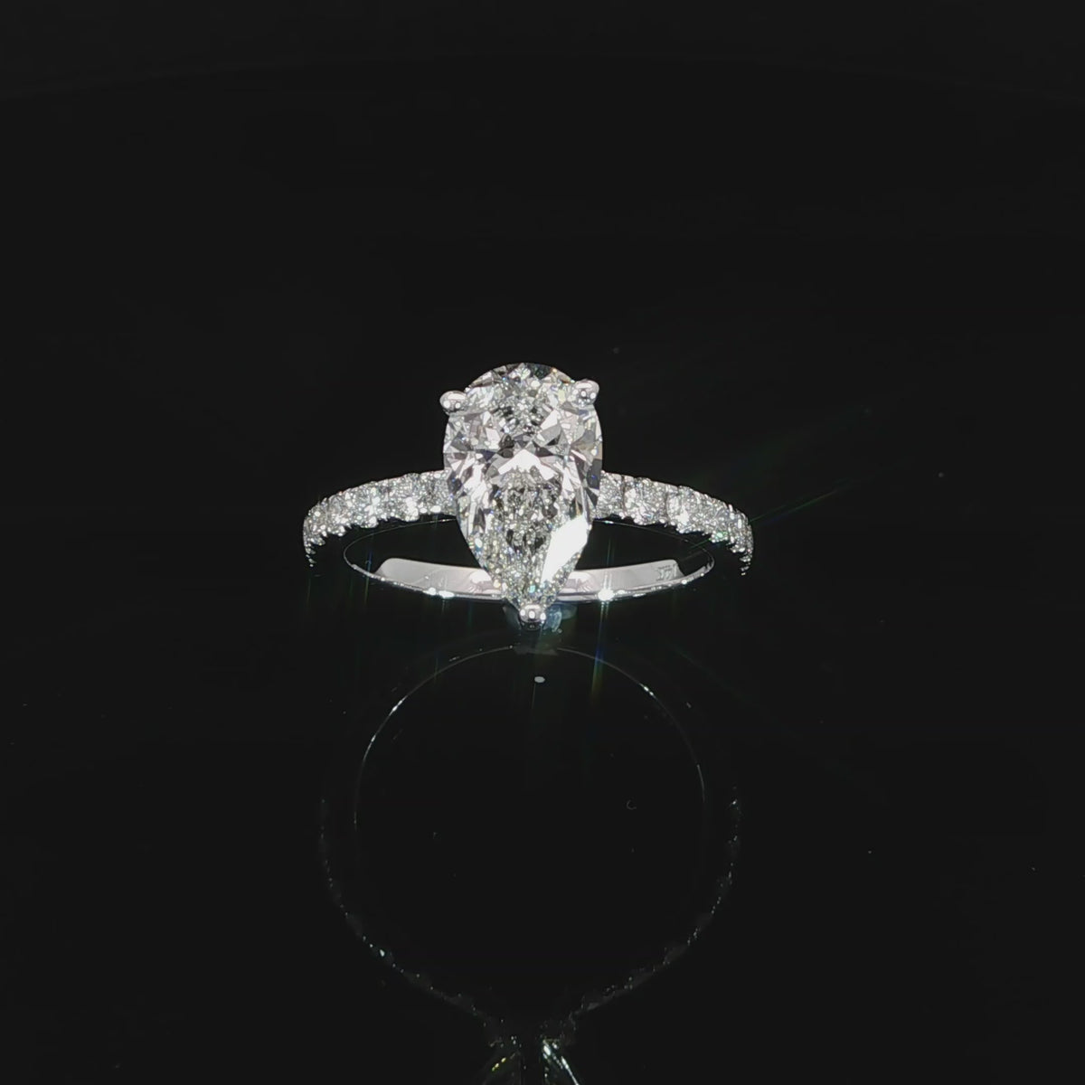 Front angle video of a white gold engagement ring with a pear center diamond and pavé-set shoulders.