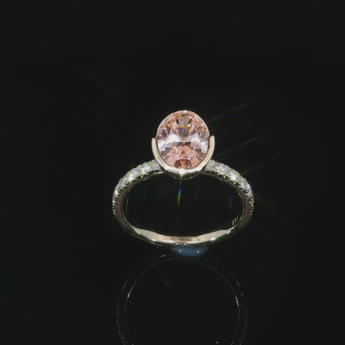Angled video of the lab grown oval fancy vivid pink diamond, polished bezel rim, and row of pave-set diamonds