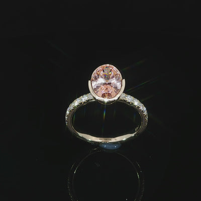 Angled video of the lab grown oval fancy vivid pink diamond, polished bezel rim, and row of pave-set diamonds