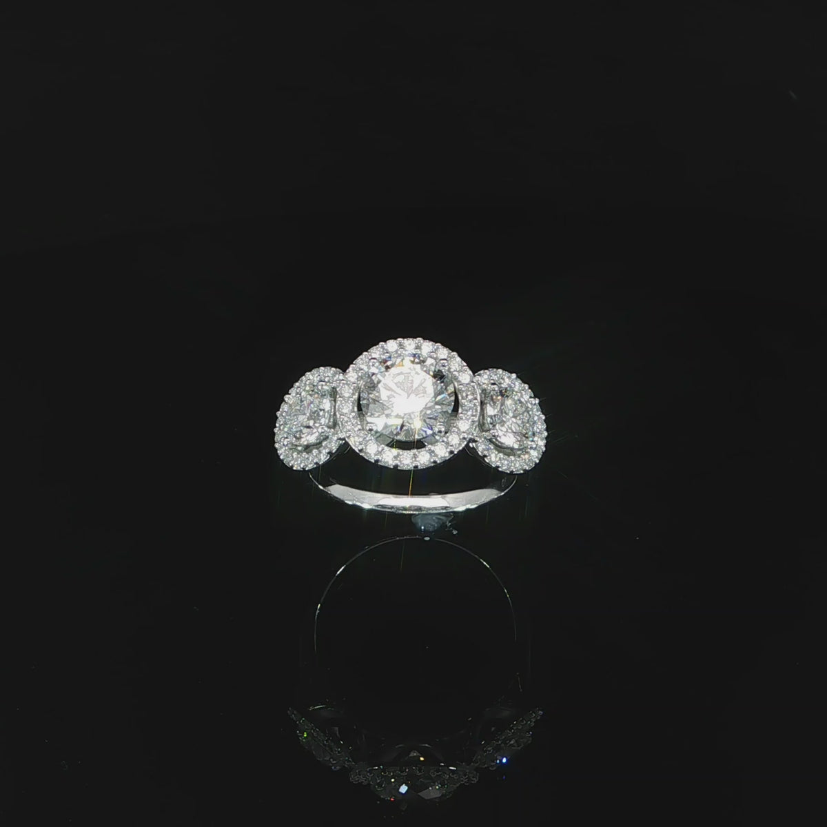 Video of three-stone arrangement with a larger round center and two halo-framed side stones