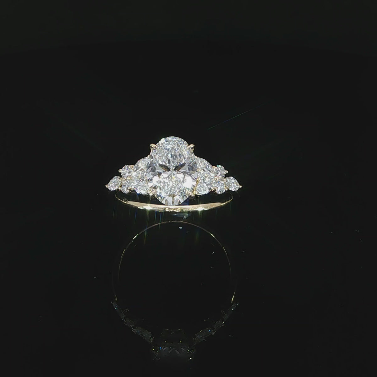 Angled video of an oval diamond engagement ring with marquise and round accents arranged along the shoulders.