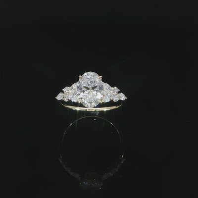 Angled video of an oval diamond engagement ring with marquise and round accents arranged along the shoulders.