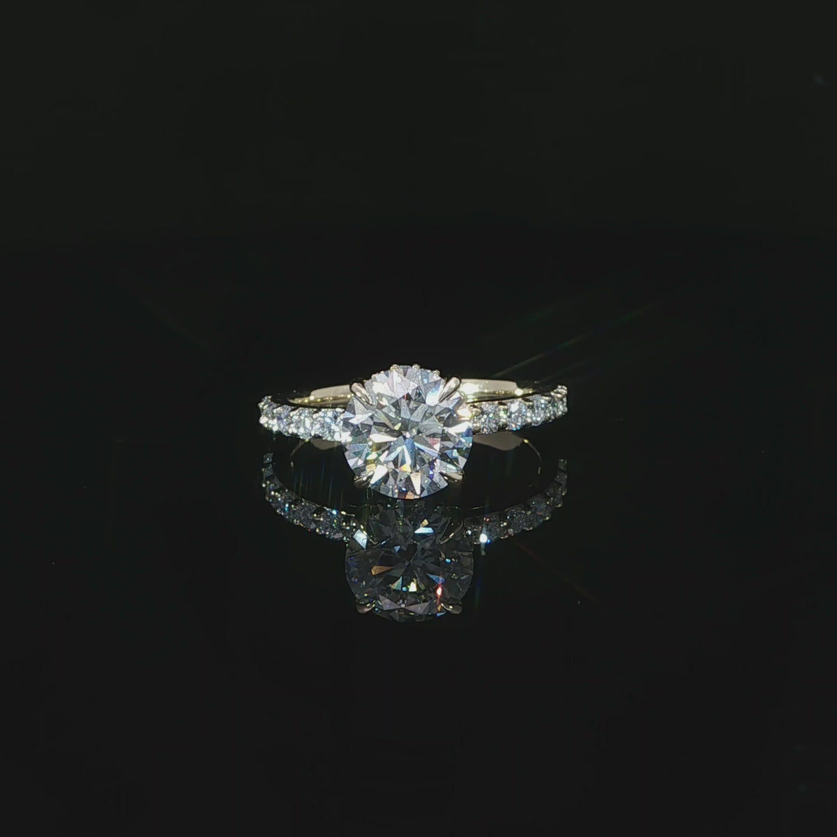 Modern round solitaire-style engagement ring with a hidden halo and diamond-accented yellow gold band.