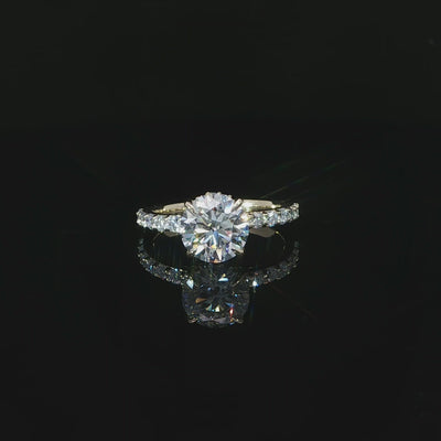 Modern round solitaire-style engagement ring with a hidden halo and diamond-accented yellow gold band.