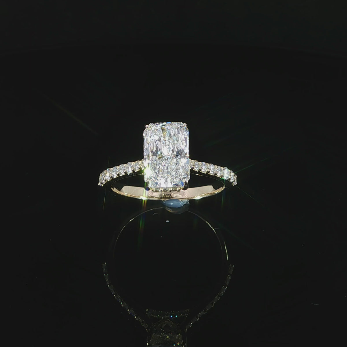 Diamond-set bridge beneath the center setting of a yellow gold radiant ring