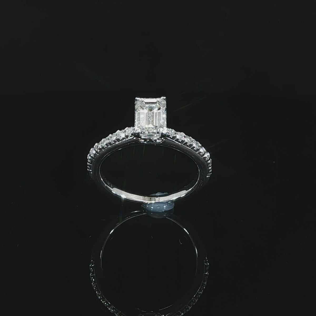 Angled emerald-cut solitaire with a diamond band, totaling 1.30 CTW, in 14K white gold against black.