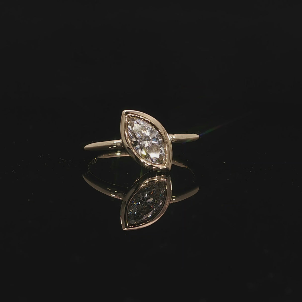 Marquise bezel diamond engagement ring in yellow gold with a sleek contemporary setting.