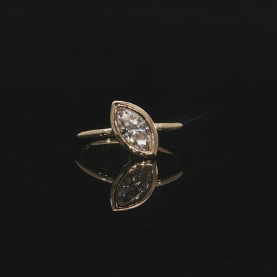 Marquise bezel diamond engagement ring in yellow gold with a sleek contemporary setting.