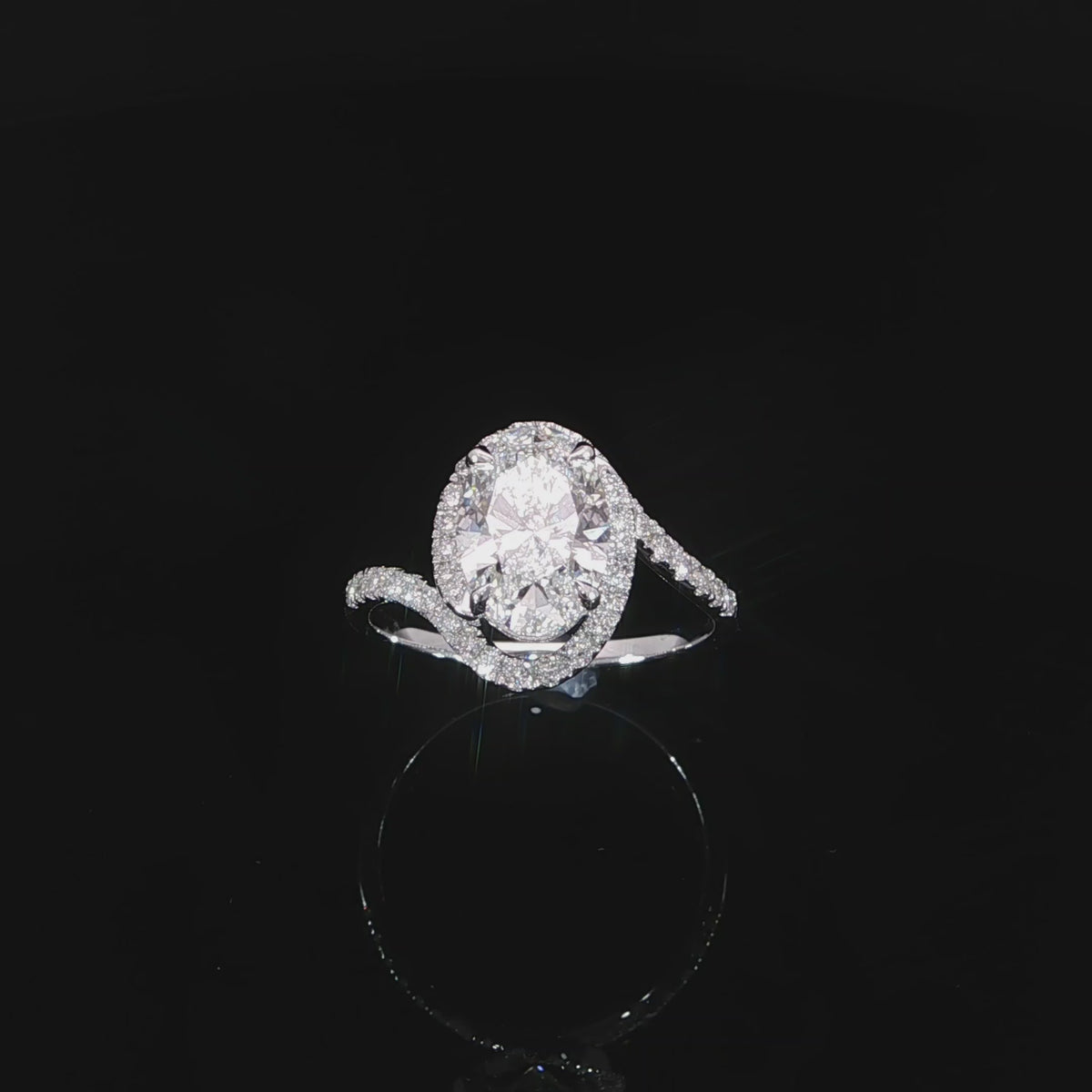 Video of angled asymmetrical oval diamond engagement ring with a sculptural bypass band and encasing halo.
