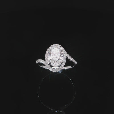 Video of angled asymmetrical oval diamond engagement ring with a sculptural bypass band and encasing halo.
