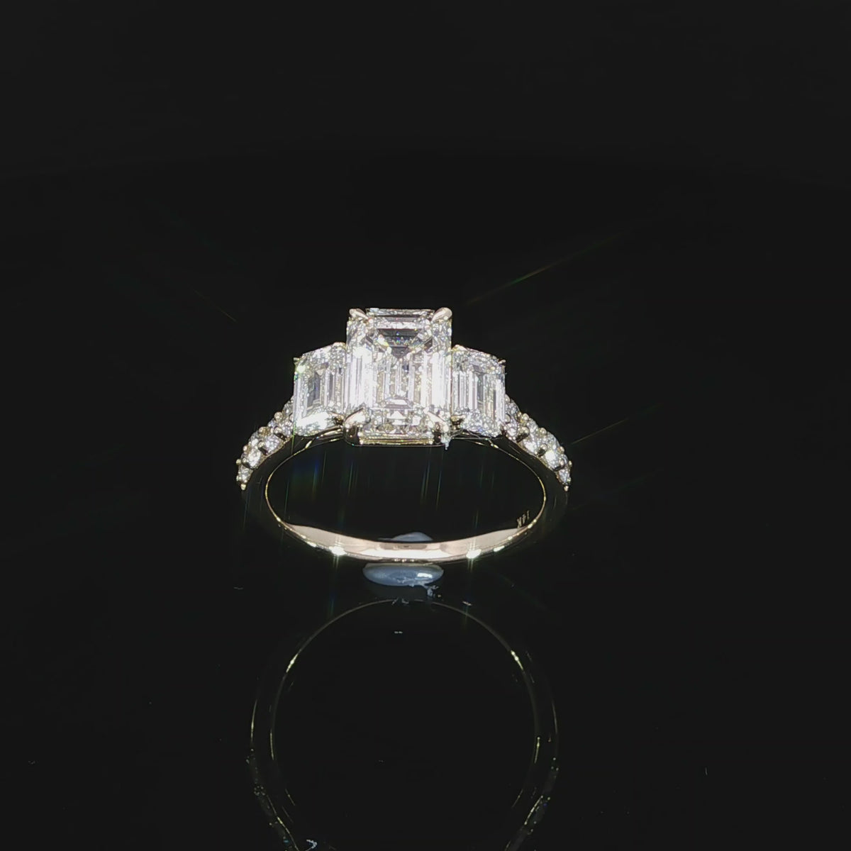 Emerald cut center diamond engagement ring with matching emerald cut side stones in a three-stone design.
