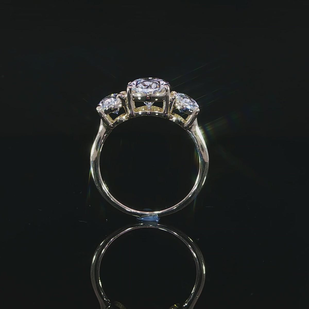 Shank view showing a larger oval center flanked by two smaller ovals in yellow gold settings.