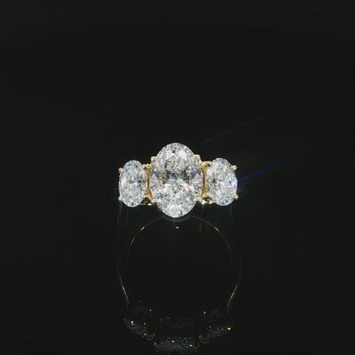 Top video view of a three-stone oval diamond ring with a polished yellow gold band.