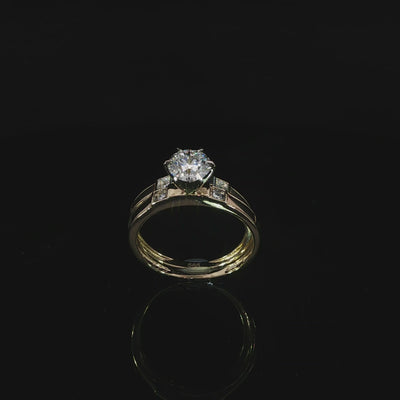 Yellow gold solitaire and matching accent band in a tilted profile with a reflection on black.