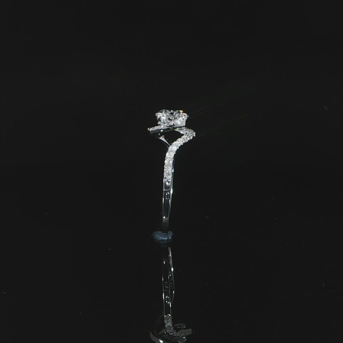 Side detail video of the raised round diamond setting above the white gold band and diamond shoulder.