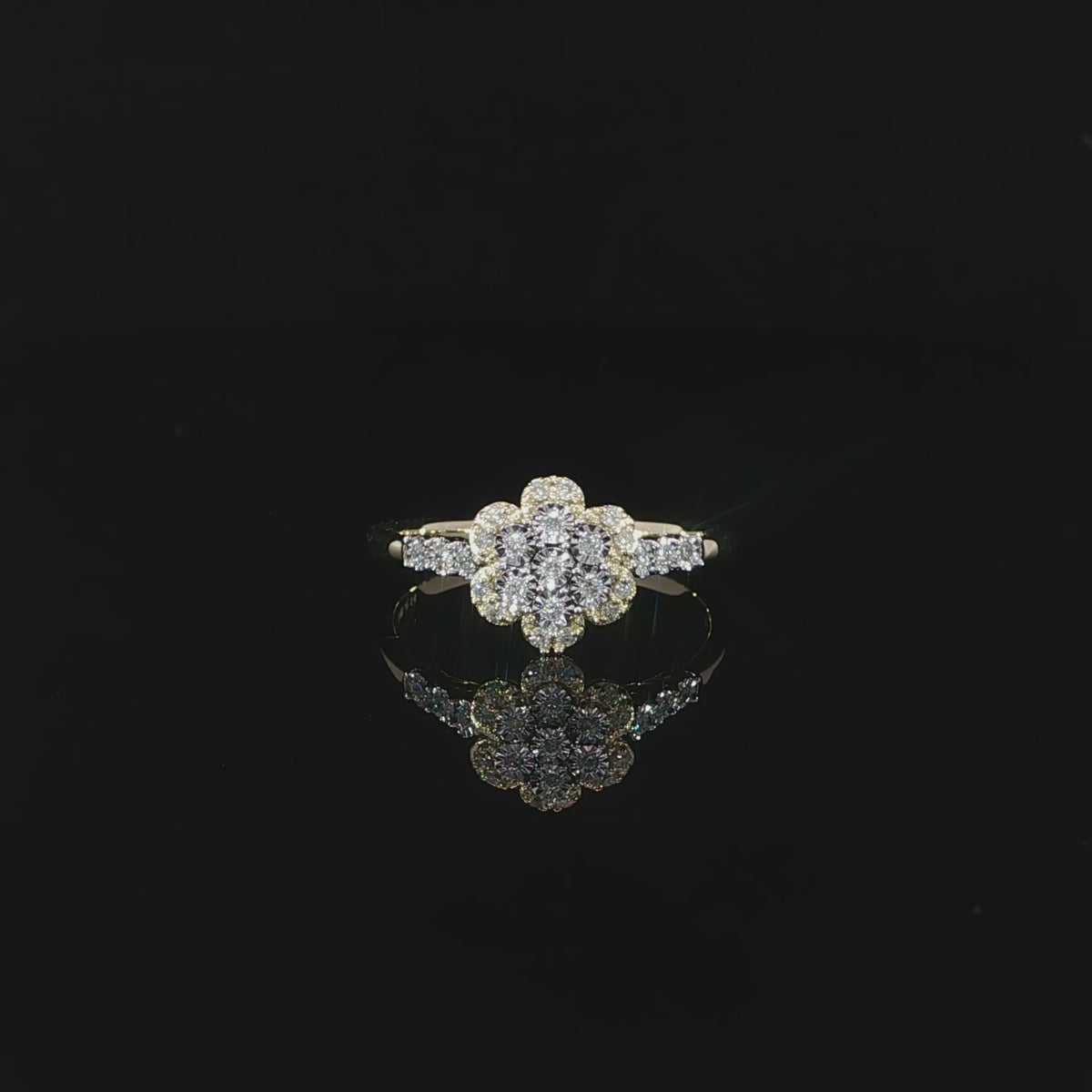 A 0.14 CTW diamond flower ring in 10K yellow gold resting above its reflection 360 video.
