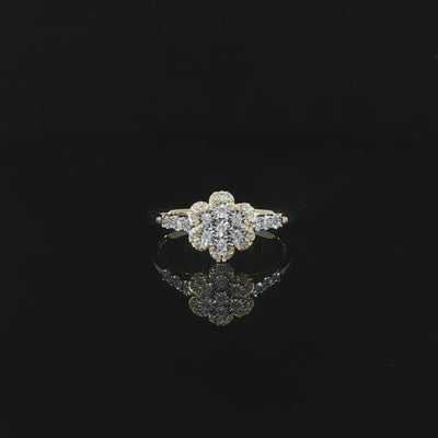 A 0.14 CTW diamond flower ring in 10K yellow gold resting above its reflection 360 video.