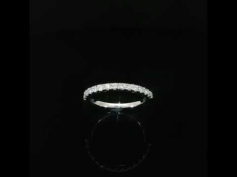 Angled view of a white gold diamond band showing small prong settings and a polished inner shank.