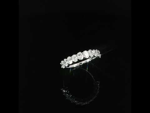 Angled oval cut diamond band with its reflection on a glossy black surface.