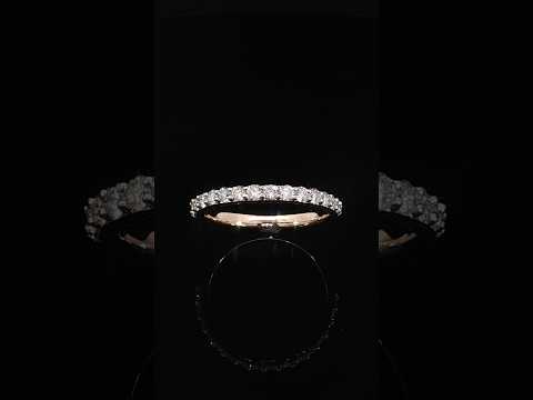 Tilted view highlighting round diamonds and polished rose gold prongs along a slender band.