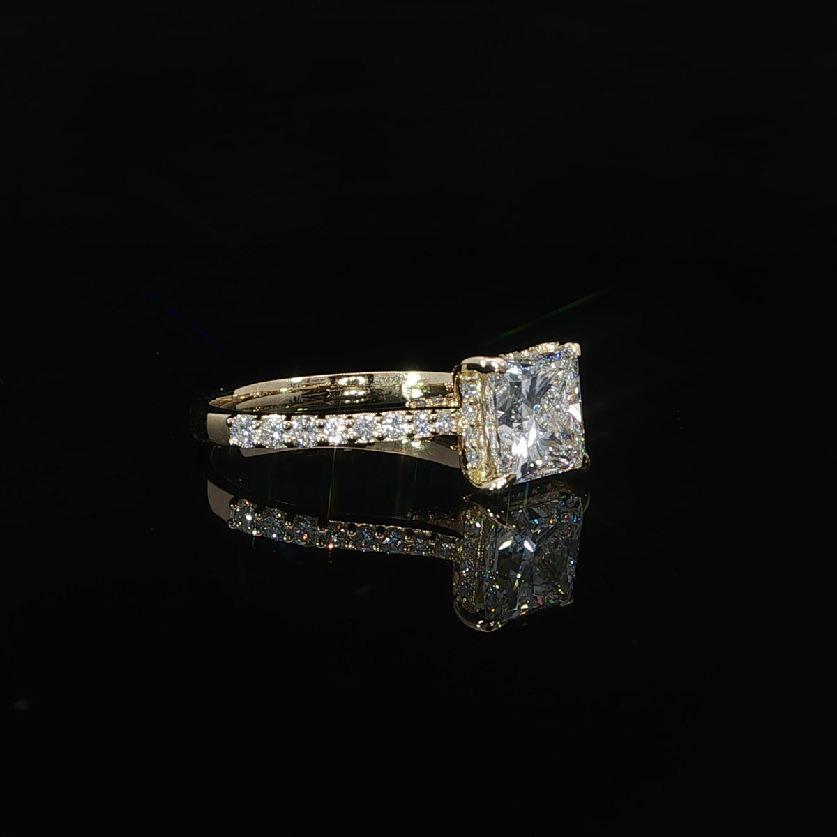 Side view of a princess cut diamond engagement ring in 14K yellow gold with a pavé diamond band.