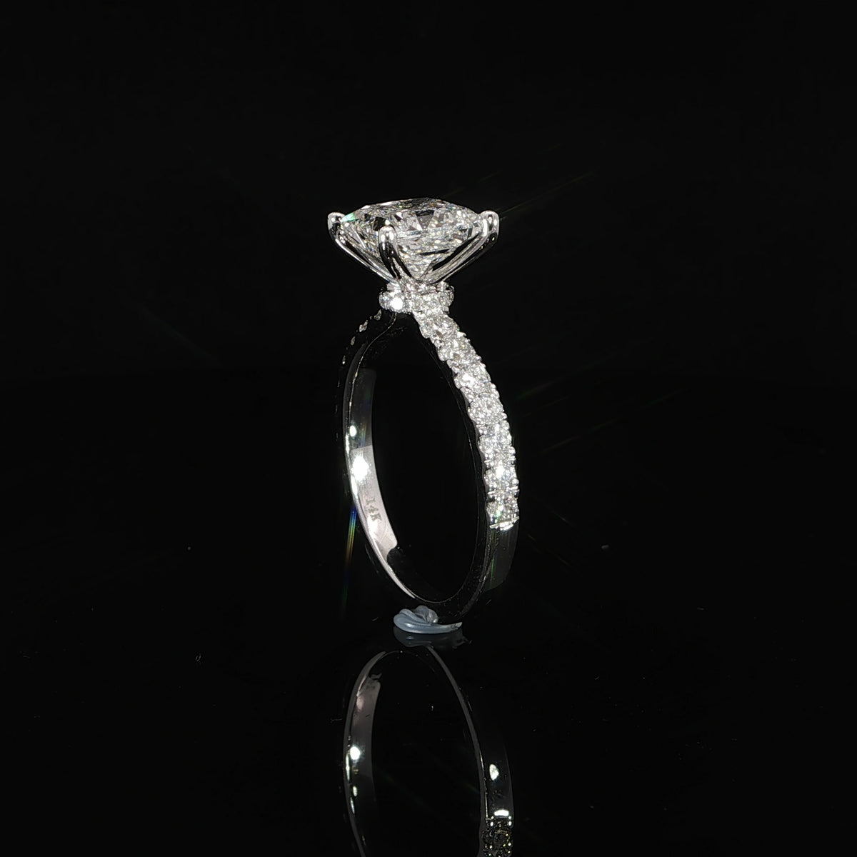 Side setting detail of white gold princess cut diamond ring with hidden halo and diamond shoulders.