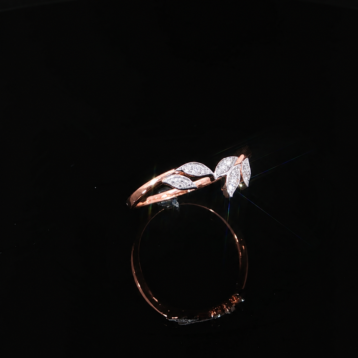 Curved leaf ring in 14K rose gold with 0.06 CTW of lab-grown diamonds, shown on a reflective black surface.