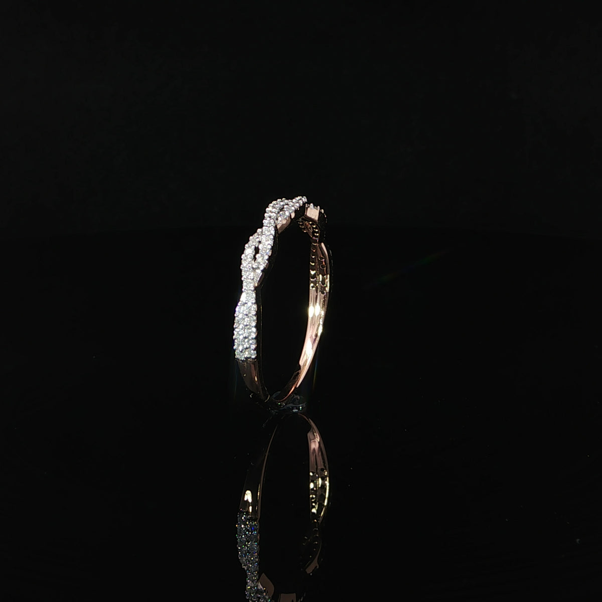 Side profile of a 14K rose gold twisted diamond wedding band showcasing its delicate setting and sparkling pavé diamonds.
