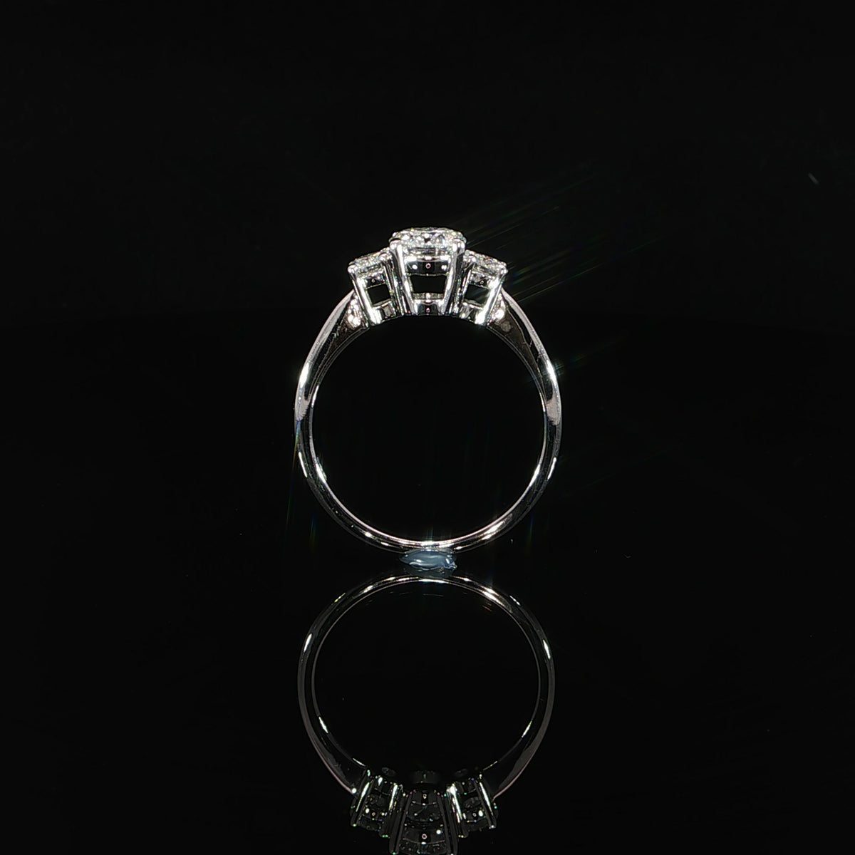 Detailed view of a round brilliant three-stone ring showing the center and side diamond settings.