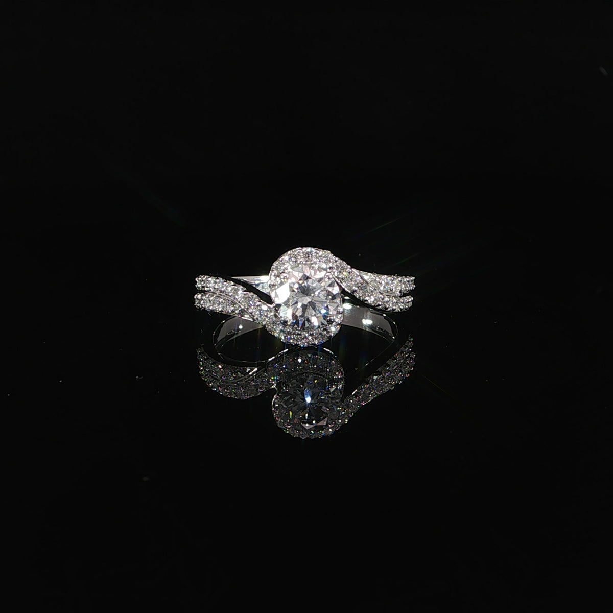Front view of a round diamond bypass engagement ring in 14K white gold with a pavé-set band.