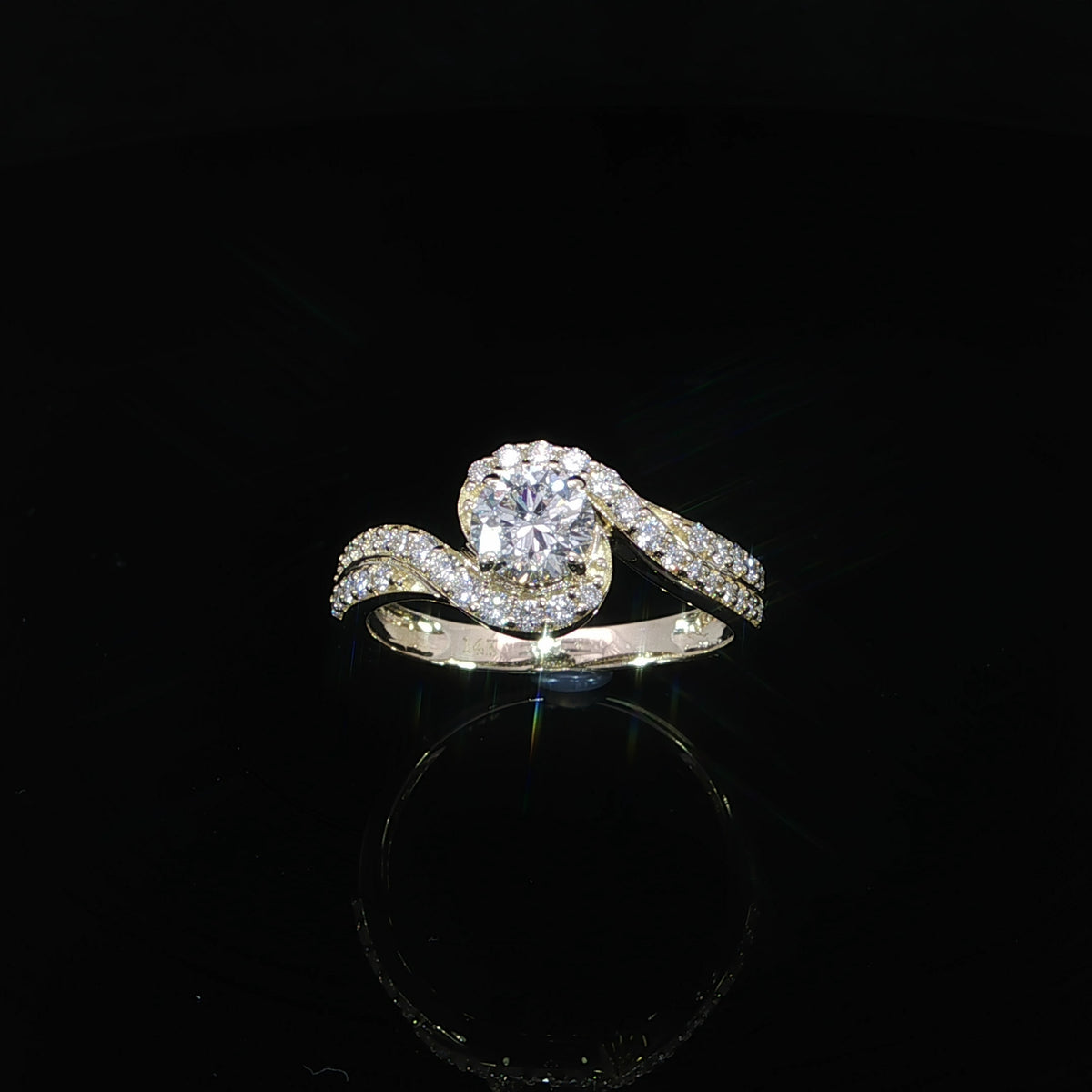 Front view of a round diamond bypass engagement ring in 14K yellow gold with a pavé-set band.