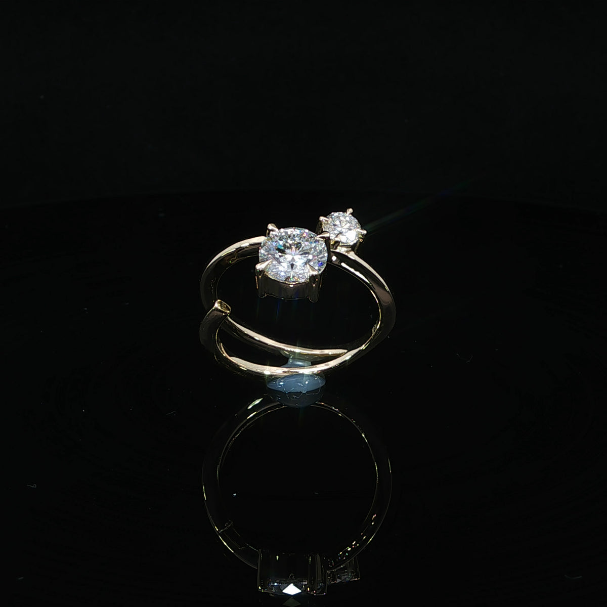 Front angle of a yellow gold ring with two round diamonds of different sizes and a polished open band.