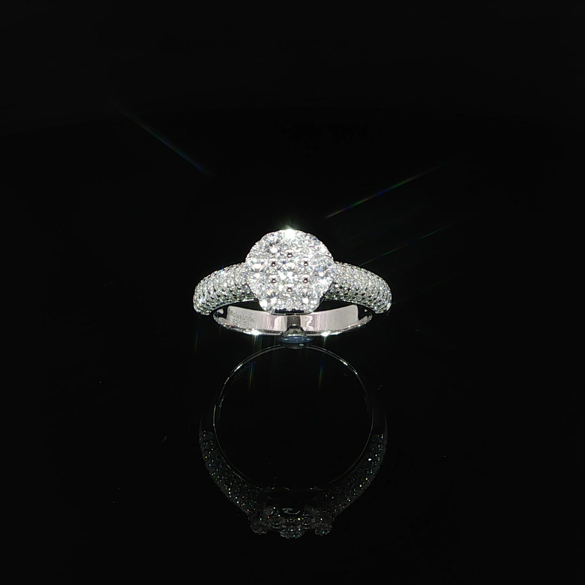 Top view of a round moissanite cluster ring with pavé-set domed shoulders.