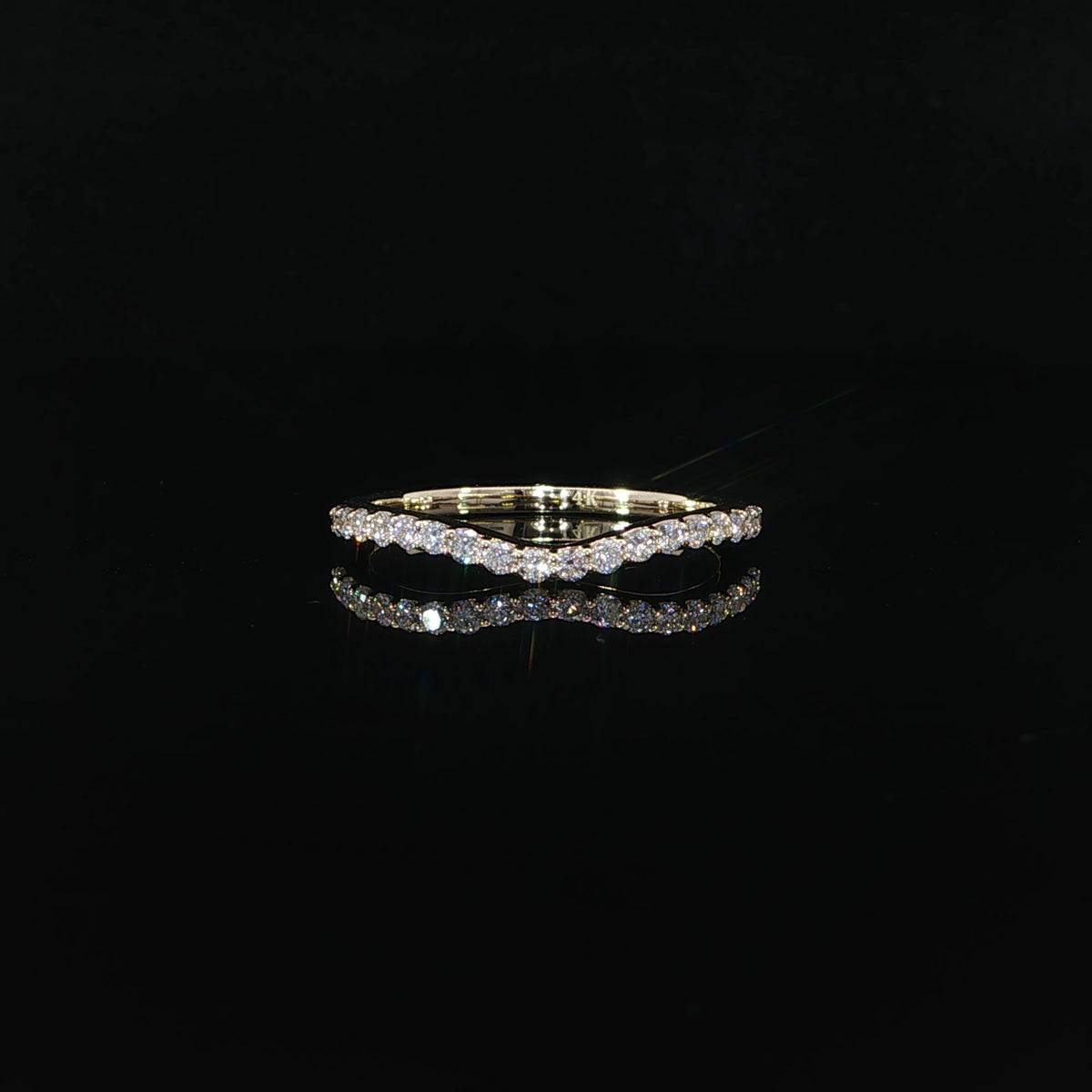 Front view of a yellow gold diamond wedding band showing its gently rounded contour.
