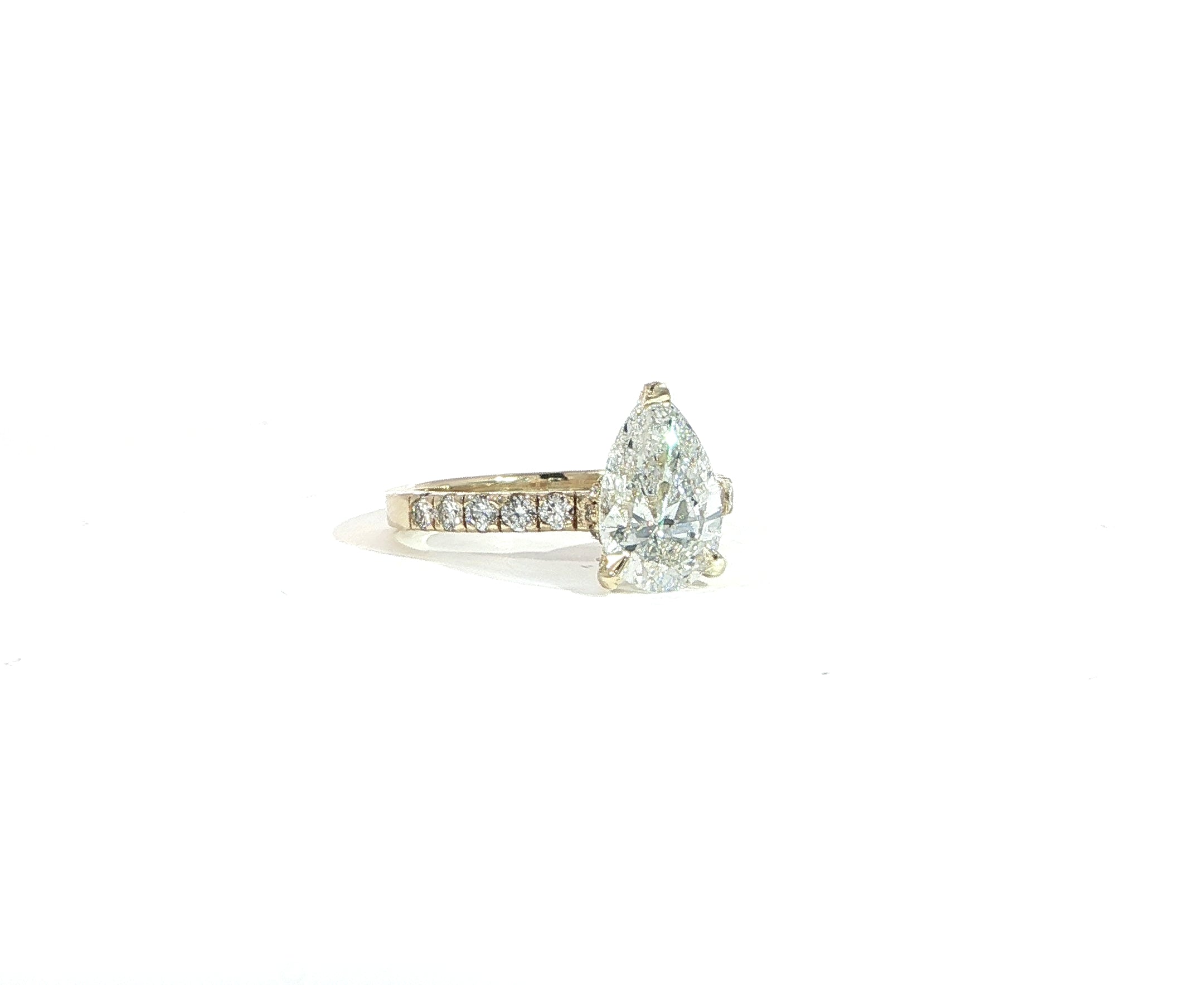 Pear-shaped diamond engagement ring with pave band