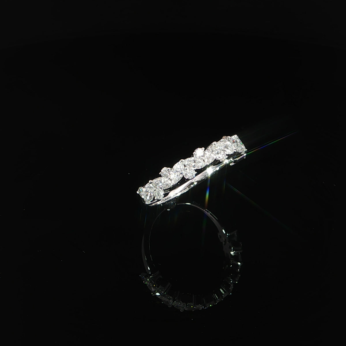 Angled detail of white gold prongs securing marquise and round diamonds across the top of a slim band.