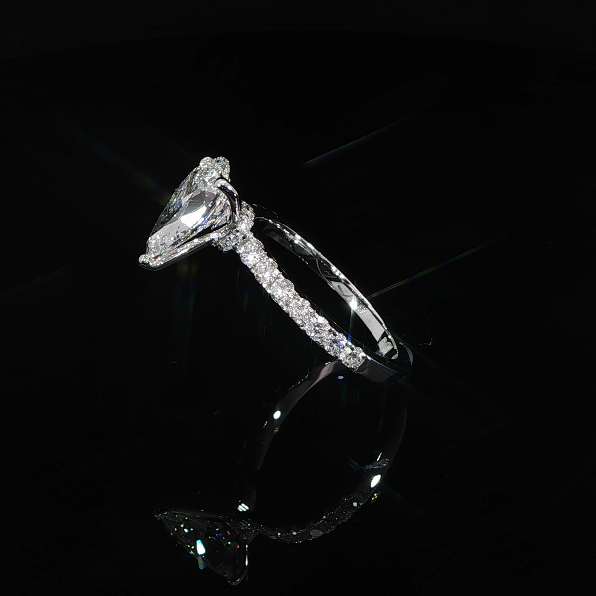 Open white gold framework supporting the pear diamond above the band.