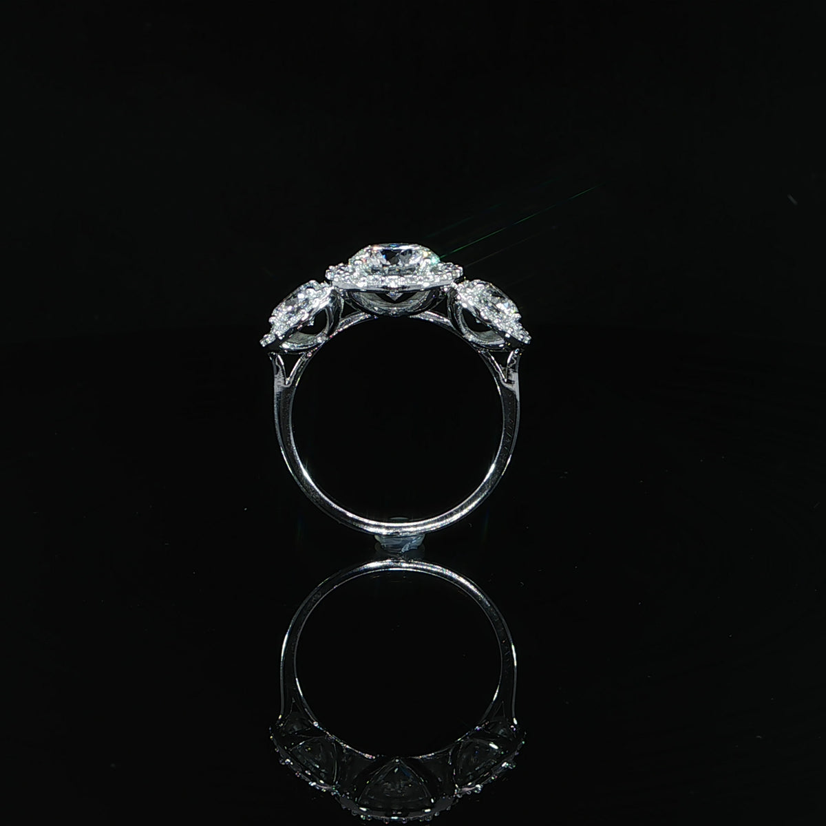 Profile of a white gold three-stone diamond halo ring showing the open gallery and polished band