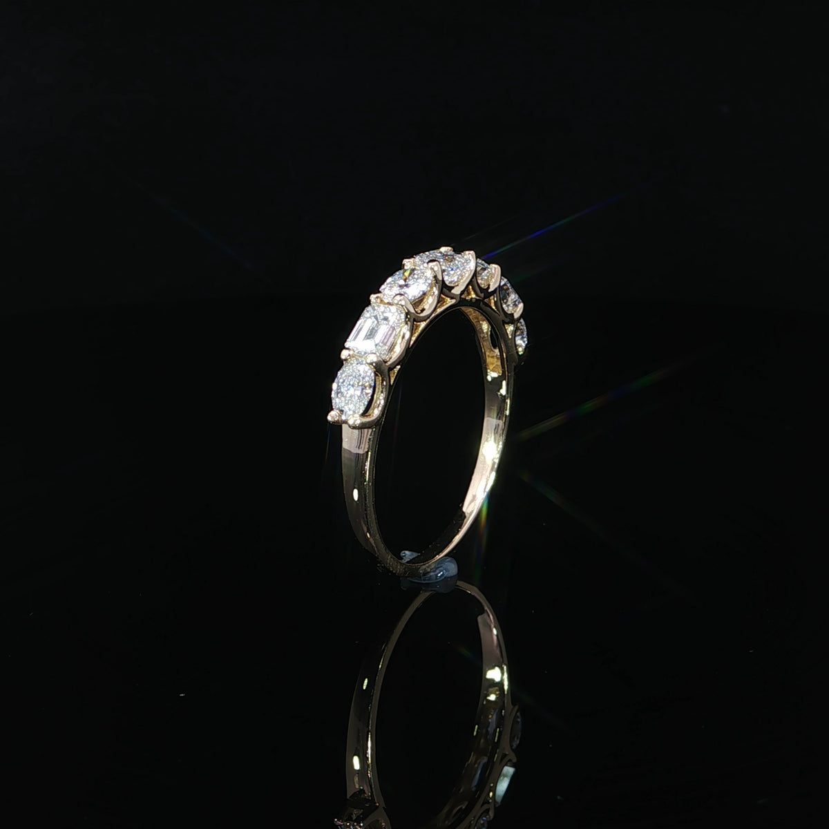 Upright side view showing the curved U-prong settings of a yellow gold diamond band.
