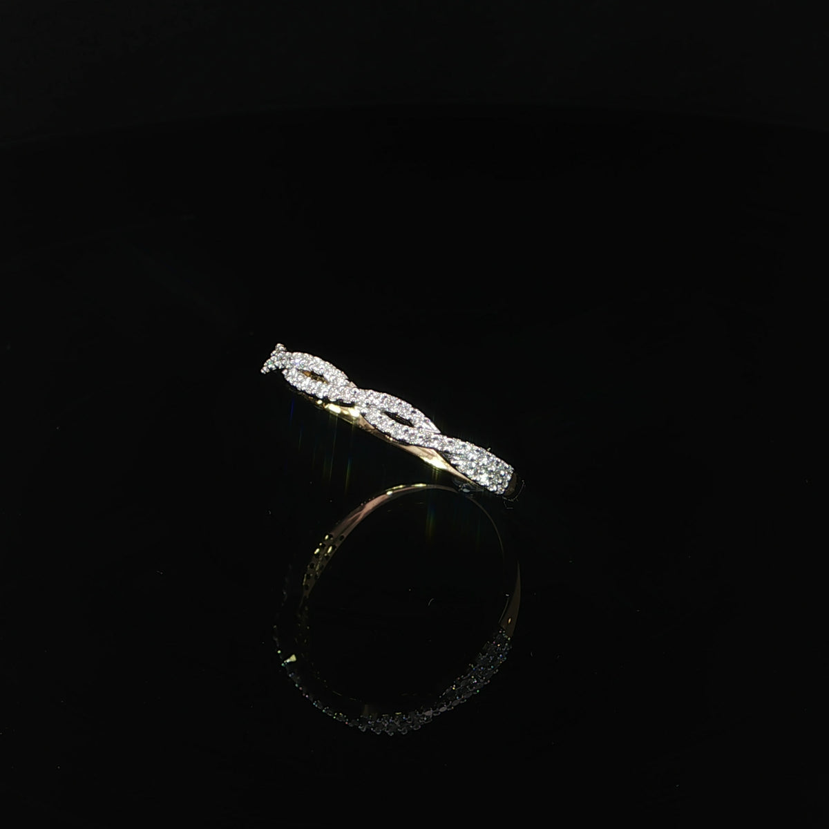 Tilted view of a lab-grown diamond twist band with open loops above a smooth yellow gold shank.