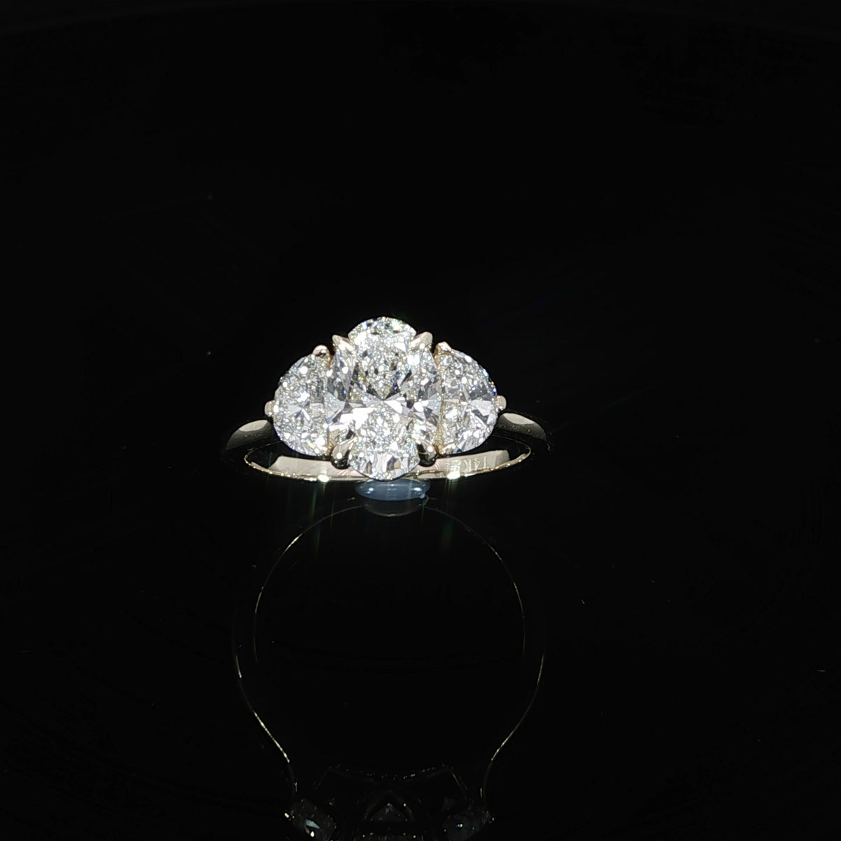 Top view of a yellow gold three-stone ring featuring an oval center diamond and half-moon side stones.