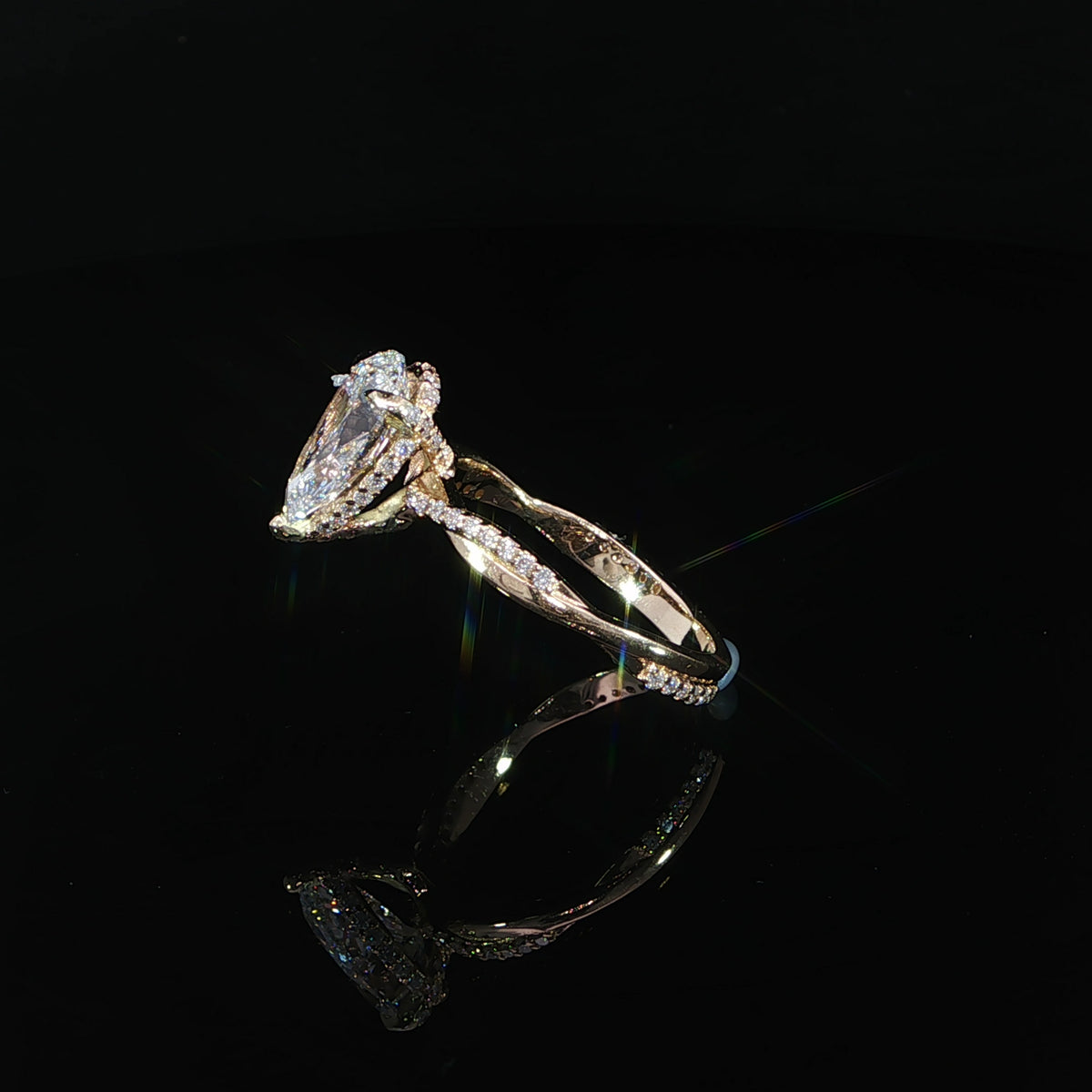 Angled view of the yellow gold pear engagement ring and diamond-accented band.