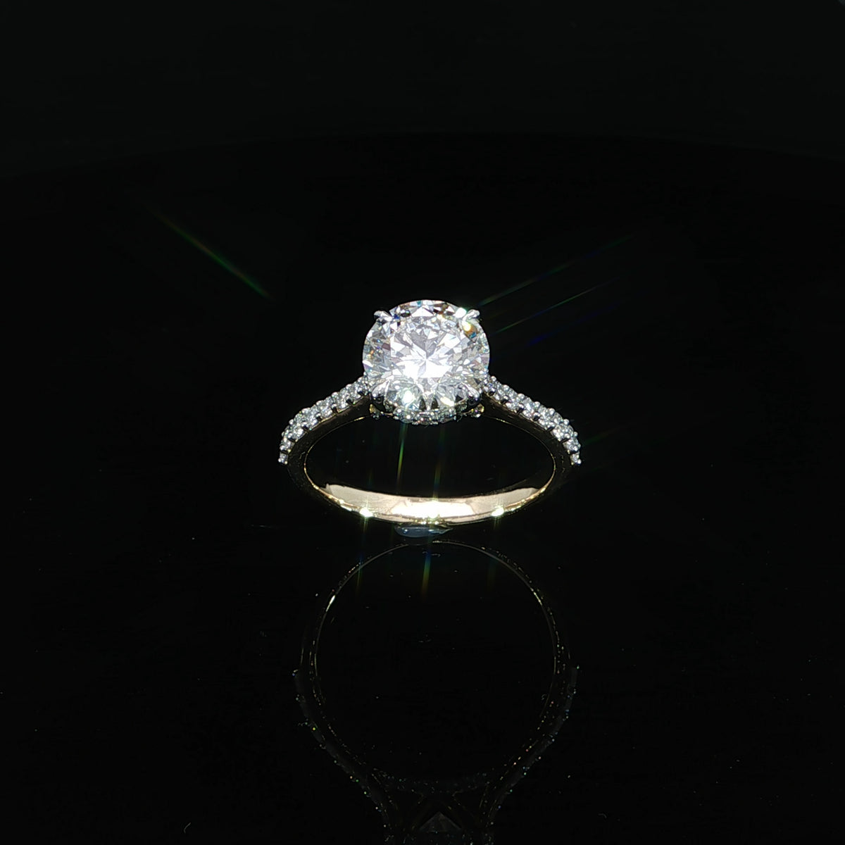 Top view of a yellow gold engagement ring with a round center diamond and diamond-accented band.