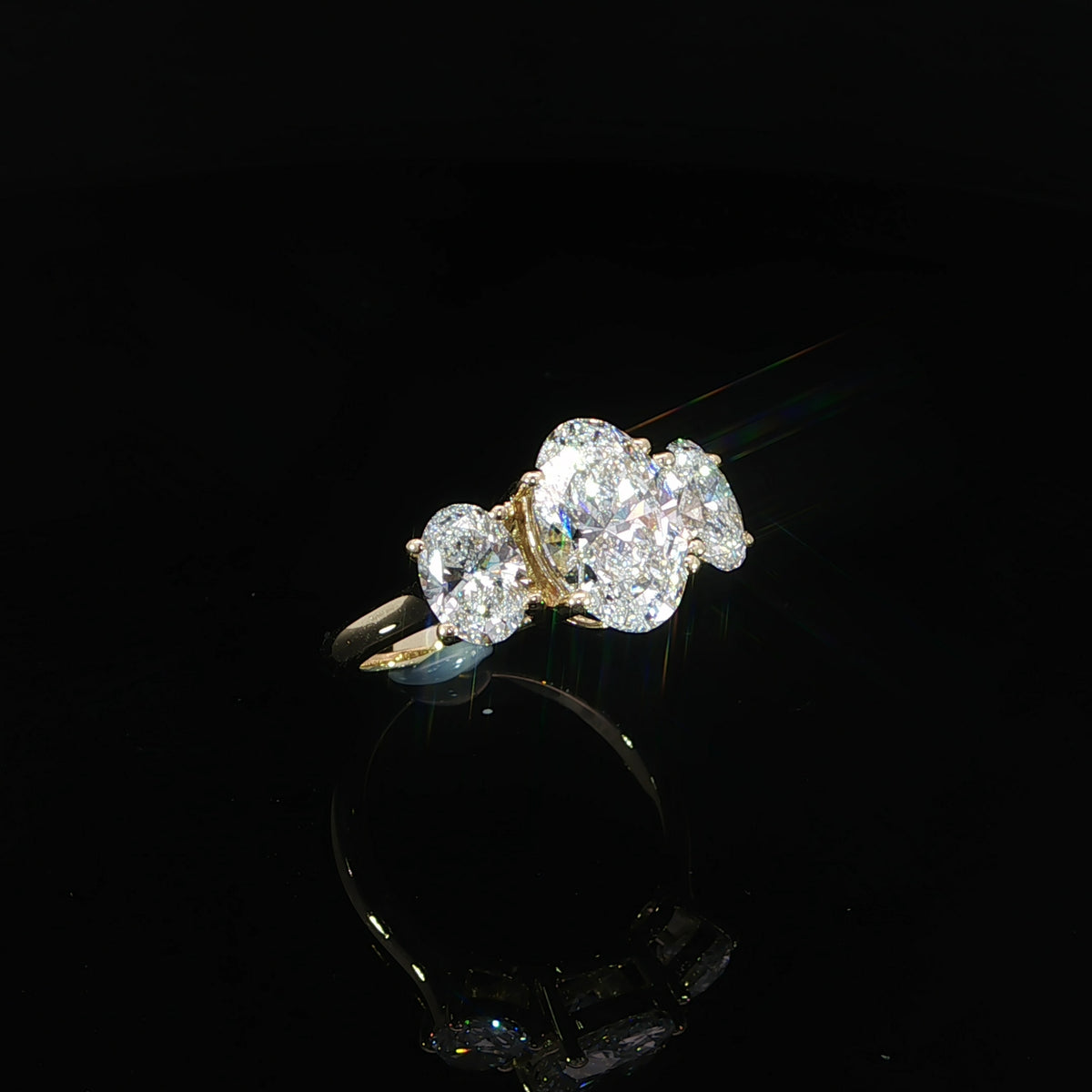 Yellow gold diamond ring positioned upright on a reflective black surface.